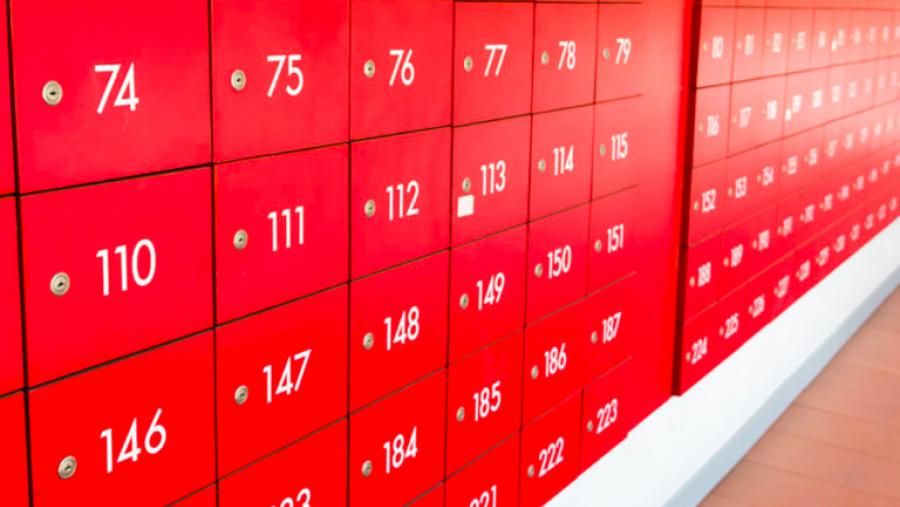 A wall of stacked red post office boxes or lockers with white numbering.