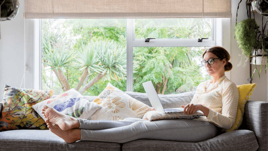 Woman relaxing with feet up on a couch and a laptop on her lap.