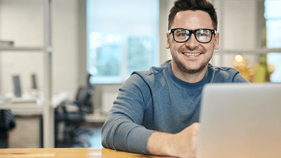 Smiling man with glasses working on laptop