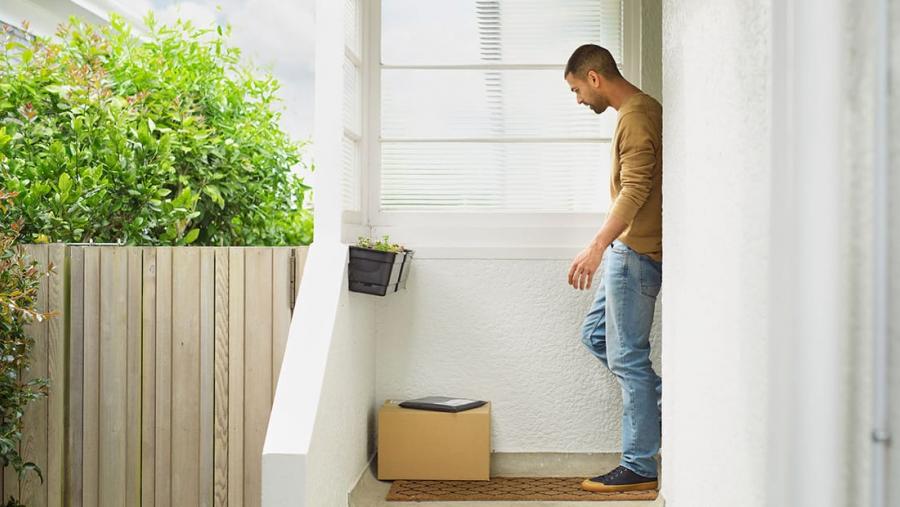 Man picking up a box and parcel delivered to his front door