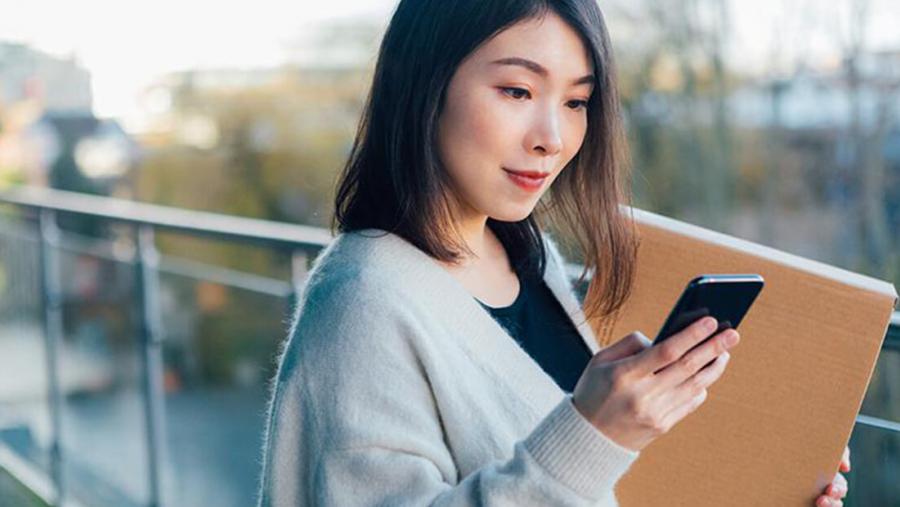 Woman holding parcel and checking her phone