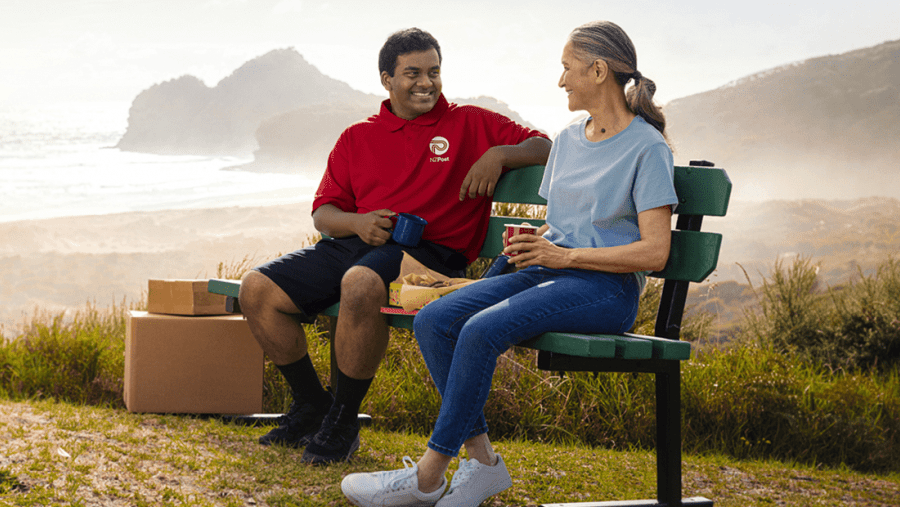 NZ Post courier and woman seated on a park bench