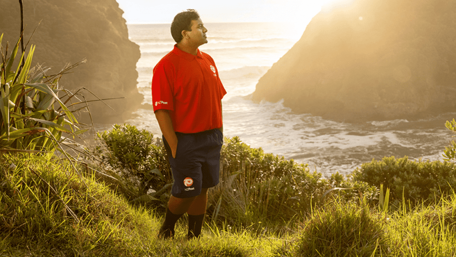 NZ Post courier in new uniform posing against scenic backdrop